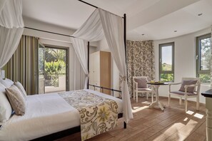 A bedroom with a four-poster bed, a sitting area with a table and chairs, and a view of greenery outside. - Alonia Villa, Refined Living with 50m² Private Pool (Rethymno)