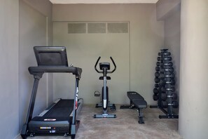 A home gym with a treadmill, elliptical, stationary bike, bench, and a rack of dumbbells.