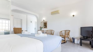 A bedroom with a large bed, a television, and a desk with a chair. - Quinta da Liberdade: studio 3 (with pool view) (Montinhos Da Luz)