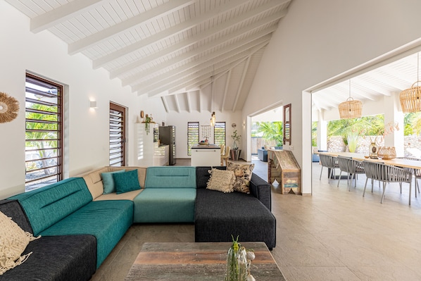 A spacious living area with a sectional sofa, a coffee table, and a dining area with chairs and a table.