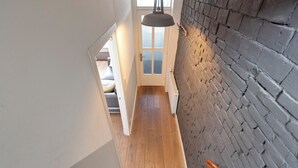 En trappe fører op til et rum med trægulv og murstensvæg.