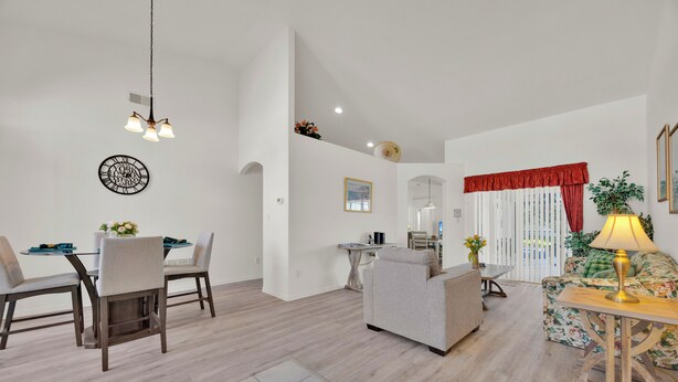 Uma sala de estar moderna com área de jantar, apresentando um sofá, cadeiras, uma mesa e um abajur.