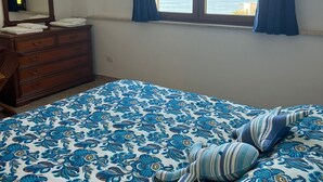 Una camera da letto con un letto, una cassettiera, uno specchio e una finestra con tende.