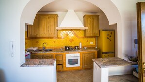 Una cucina con mobili in legno, un fornello, un forno e un frigorifero giallo.