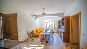 Un'ampia sala da pranzo con un tavolo lungo, sedie di legno e una finestra luminosa.