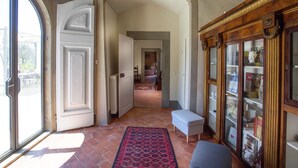 A hallway with a red patterned rug, a white bench, and a wooden bookcase.