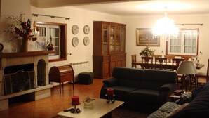 Una sala de estar con chimenea, sofá, mesa de comedor y candelabro.