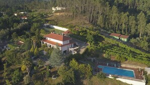 Una extensa propiedad con varias construcciones, piscina y abundante vegetación.