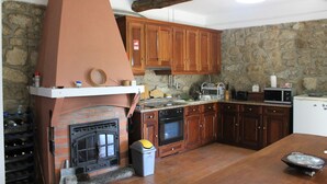 Una cocina con armarios de madera, pared de piedra, chimenea de ladrillo y microondas moderno.