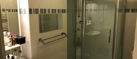 A modern bathroom with a glass-enclosed shower, a white sink, and a mirror above it.