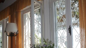 Ein Zimmer mit einem Holztisch, einem Stuhl, einer Lampe und einem Fenster mit Vorhängen.