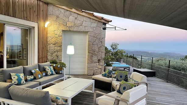 Un patio al aire libre con un muro de piedra, una terraza de madera y vistas del paisaje.