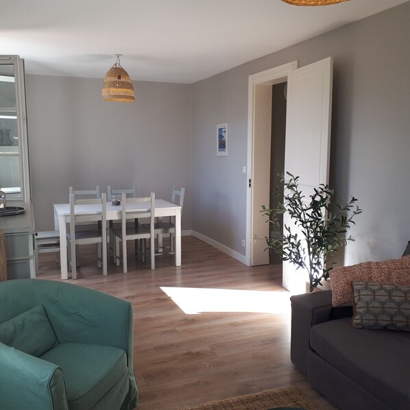 A dining area with a white table and chairs, a hanging light fixture, and a doorway leading to another room.