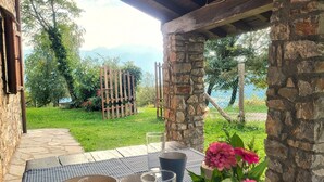 A table set with a bowl, cup, and glass, a vase with flowers, and a view of a stone wall and greenery. - Fabulous Spectacularly Located Romantic Cottage With Private Infinity Pool (Carregine)