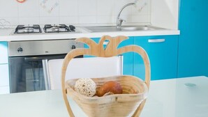 Een keuken met een wit aanrecht, een gasfornuis, een spoelbak en blauwe kastjes.