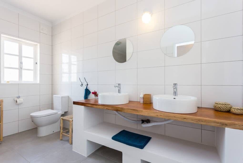 Ein modernes Badezimmer mit zwei Waschbecken, einer Toilette und einem Fenster.