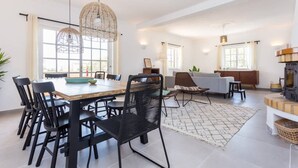 A modern living room with a dining area, large windows, and a fireplace.