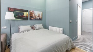 A bedroom with a bed, two wall-mounted pictures, a floor lamp, and a door leading to another room. - BED AND BREAKFAST ONLY HUERTAS-2 (Madrid)