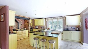 A kitchen with yellow cabinets, a large island with stools, and a window providing natural light.