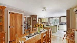 A spacious kitchen with wooden cabinets, a dining area with a wooden table and chairs, and a view of the garden through the window.