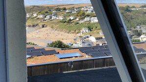 A coastal view with houses on a hillside, a beach, and solar panels on the roof. - Westward 14, Polzeath, North Cornwall  (Polzeath)