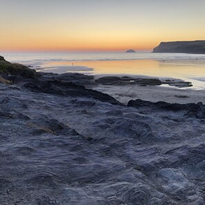 Ein felsiger Strand mit ruhigem Wasser und blauem Himmel.