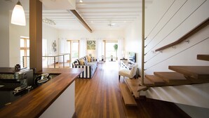 A spacious living area with a wooden floor, a kitchen with a wooden countertop, and a staircase with wooden steps. - Stunning Hillside Villa, Limegrove St James (Holetown)