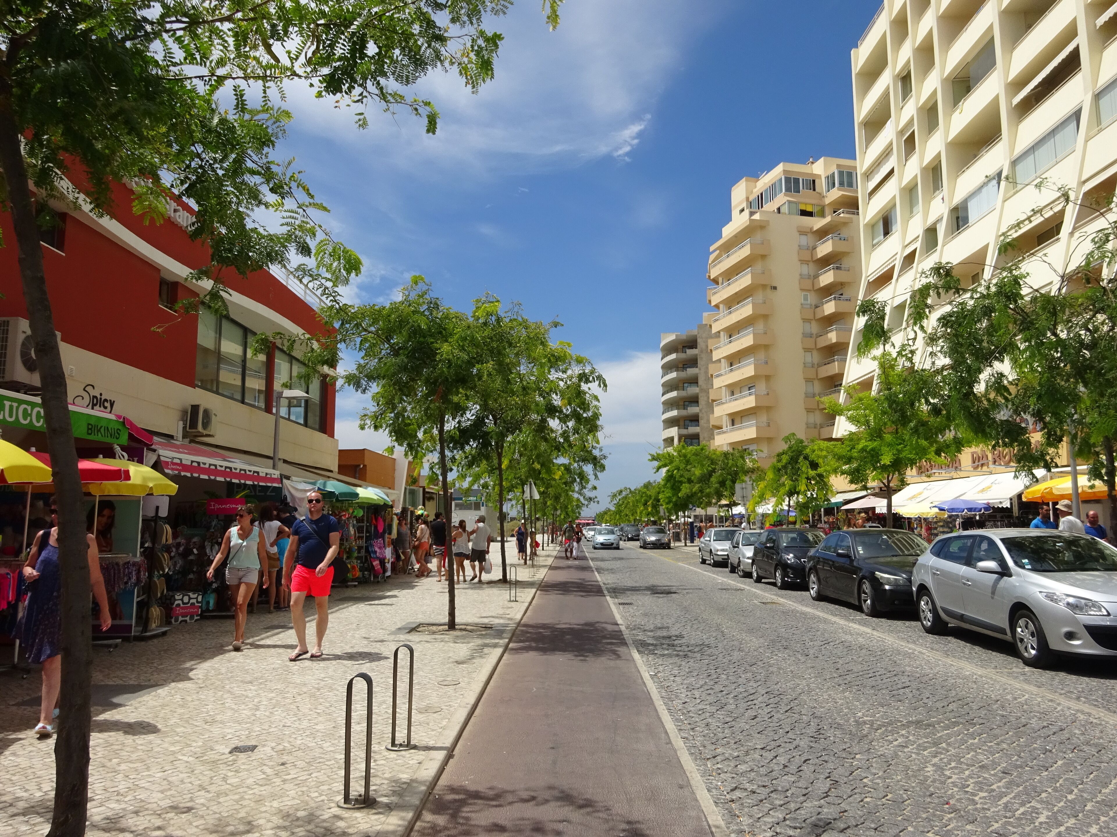 A street lined with shops and a tall building with balconies.