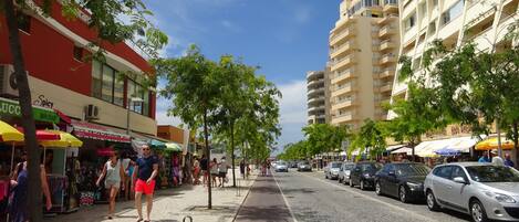 A street lined with shops and a tall building with balconies.