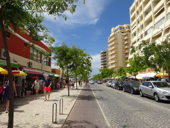 Una calle bordeada de tiendas y un edificio alto con balcones.