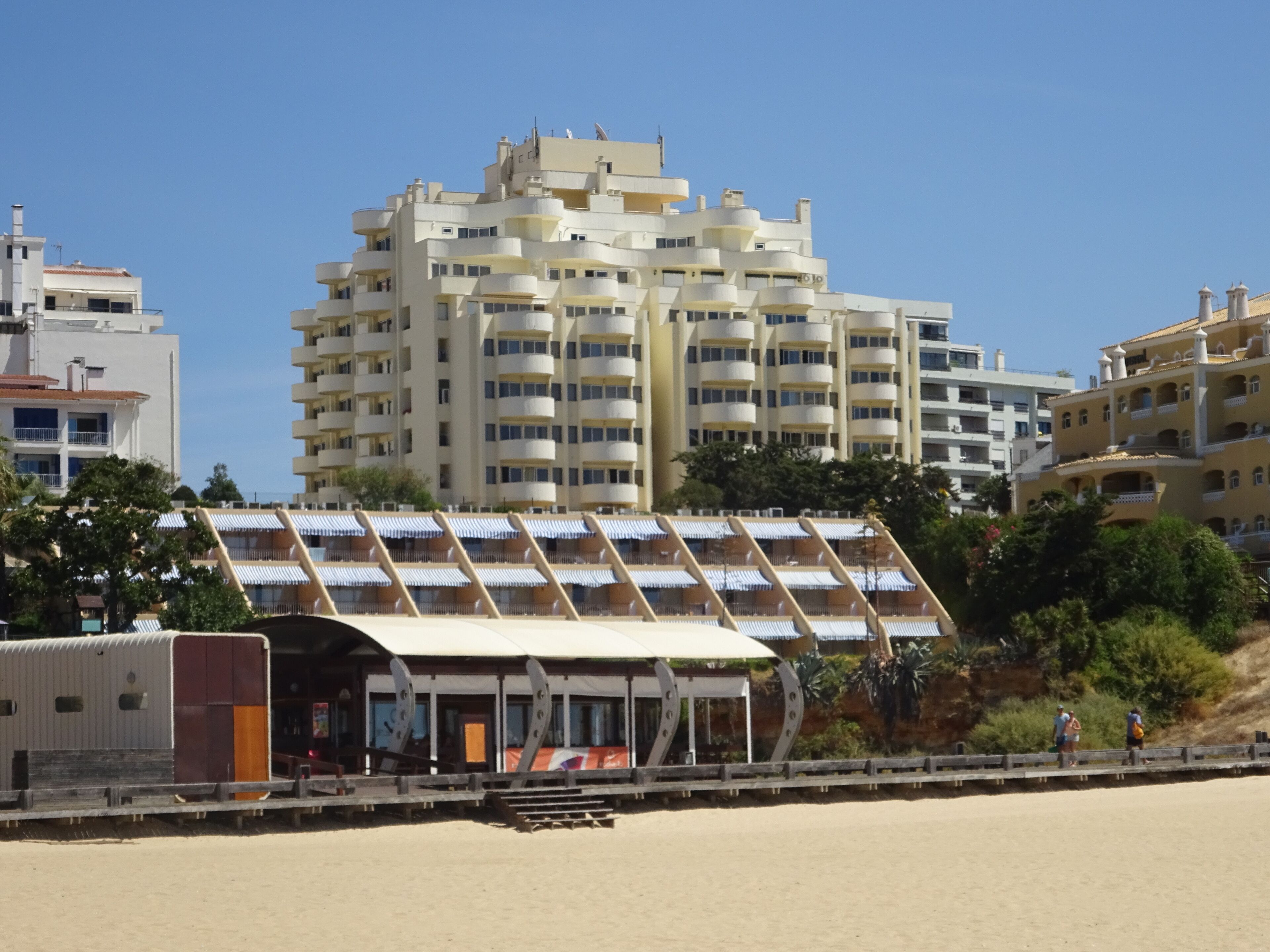 Un hôtel en bord de mer au design moderne, doté d’un espace extérieur couvert et de plusieurs balcons.