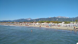 A beach with people swimming and walking, umbrellas, and boats. - APARTMENT IN VILLA WITH GARDEN AND SEA VIEW (La Spezia)