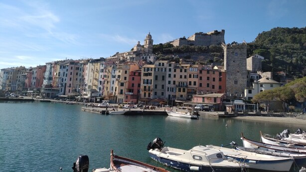A coastal town with colorful buildings, a castle on a hill, and boats docked at the harbor. - APARTMENT IN VILLA WITH GARDEN AND SEA VIEW (La Spezia)