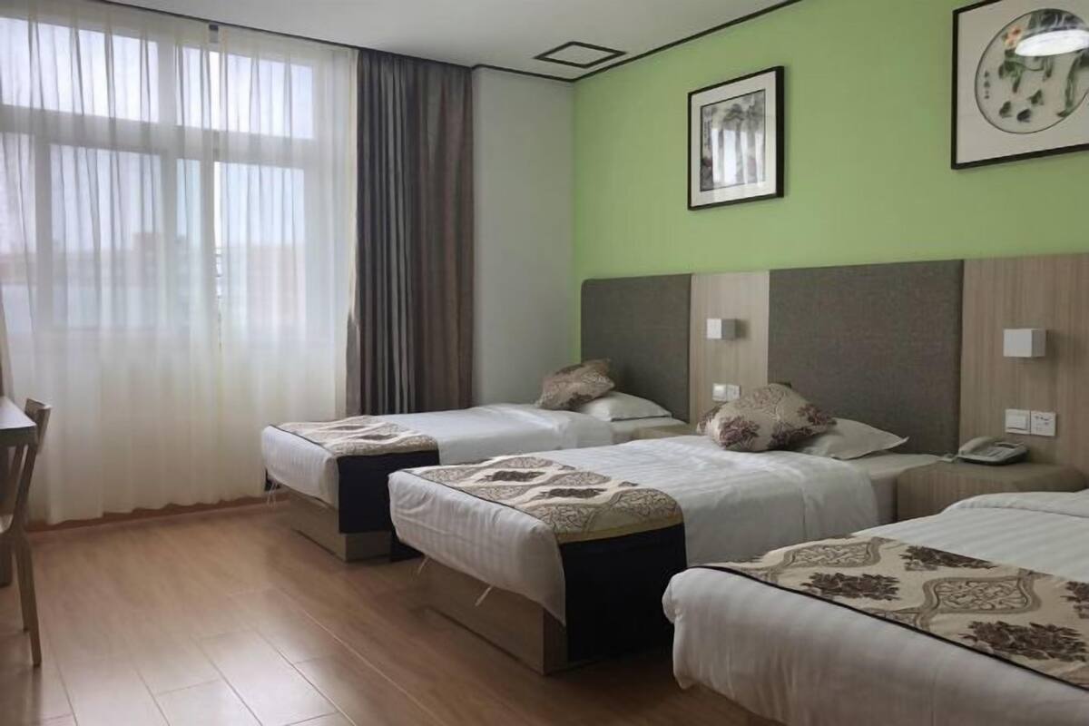 A hotel room with three beds, a desk, and a chair.