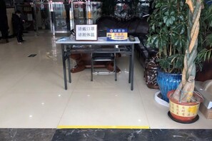 A reception desk with a sign, a potted plant, and a blue vase. - Nongjun Hotel (Beijing)