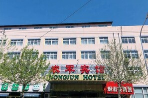 Un edificio con un cartel que dice 'MONGJUN HOTEL' y un letrero rojo que dice 'Nongyun Hotel'.