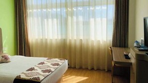 A hotel room with a bed, a desk, and a large window with sheer curtains. - Nongjun Hotel (Beijing)