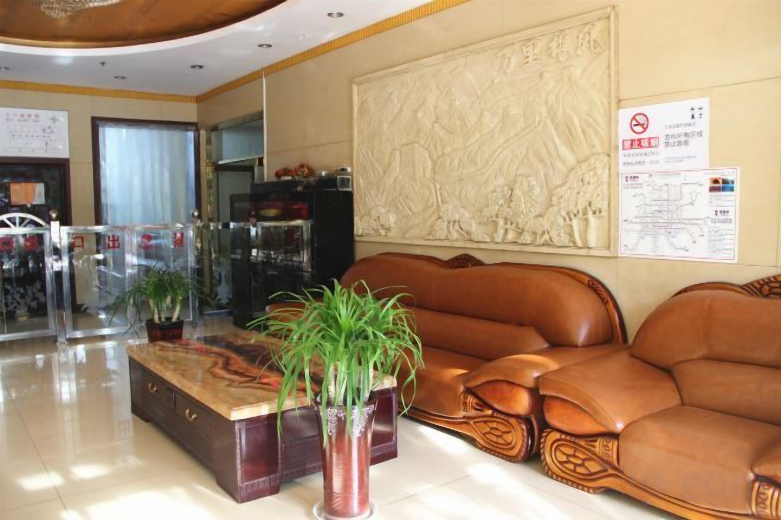 A lobby with a reception desk, seating area, and a wall with a decorative relief.