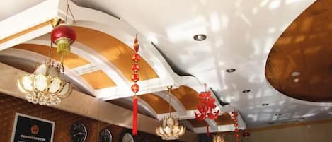 Interior de hotel con candelabros, detalles en rojo y relojes en la pared.