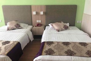 A hotel room with two beds, each with a floral-patterned bedspread, a wooden headboard, and a nightstand with a telephone. - Nongjun Hotel (Beijing)