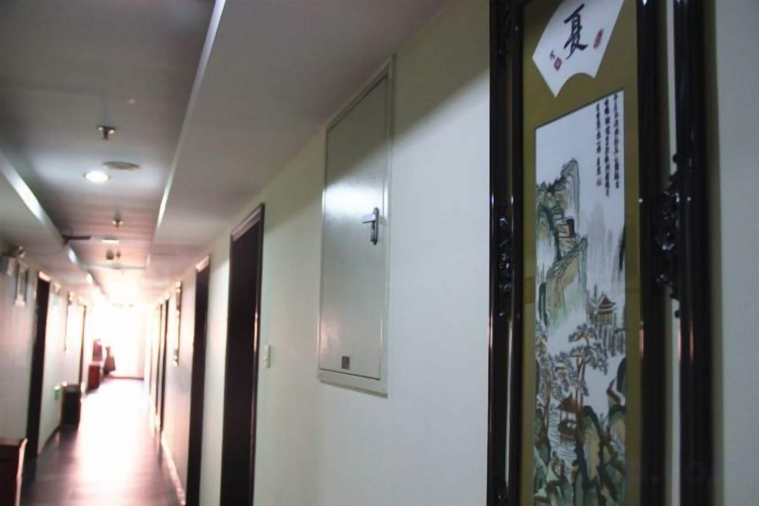 A hallway with doors on one side and a poster on the wall.