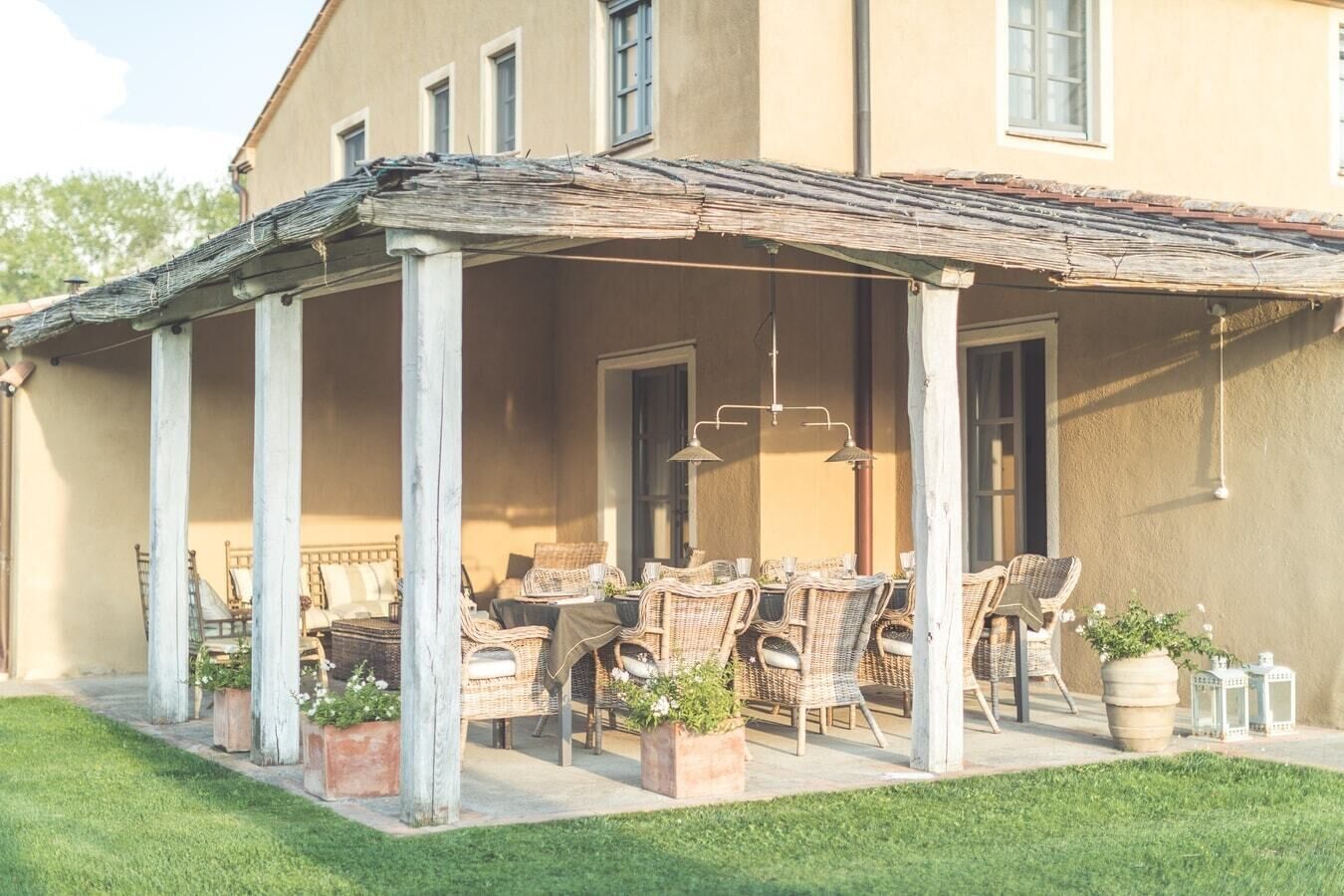A covered patio with wicker furniture and potted plants.