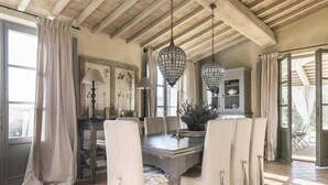 A dining area with a wooden table, white chairs, and hanging crystal chandeliers. - Villa Sulle Colline - Tuscan villa with private pool (San Casciano dei Bagni)