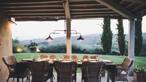 An outdoor dining area with wicker chairs and tables, a pergola, and a view of hills and trees. - Villa Sulle Colline - Tuscan villa with private pool (San Casciano dei Bagni)