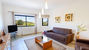 Ein modernes Wohnzimmer mit einer Couch, einem Couchtisch, einem Fernseher und Kunstwerken an den Wänden.