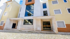 Ein modernes, mehrgeschossiges Gebäude mit einer zentralen Treppe, großen Fenstern und einem Kopfsteinpflaster-Eingang.