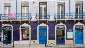 Una fila de edificios con baldosas azules y blancas y balcones, cada uno con un letrero para un restaurante llamado 'Arouivo Geral'.