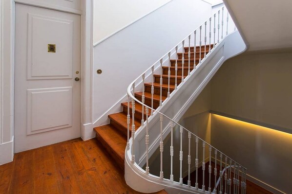 A staircase with wooden steps and white balusters, leading to a landing with a white door.