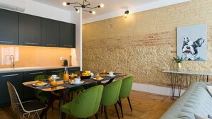 Una cocina moderna con armarios oscuros, un espacio para desayunar y una pared de ladrillo.