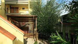 A yellow building with a covered outdoor area and a wooden fence. - Residential flat with garden (Scarlino)